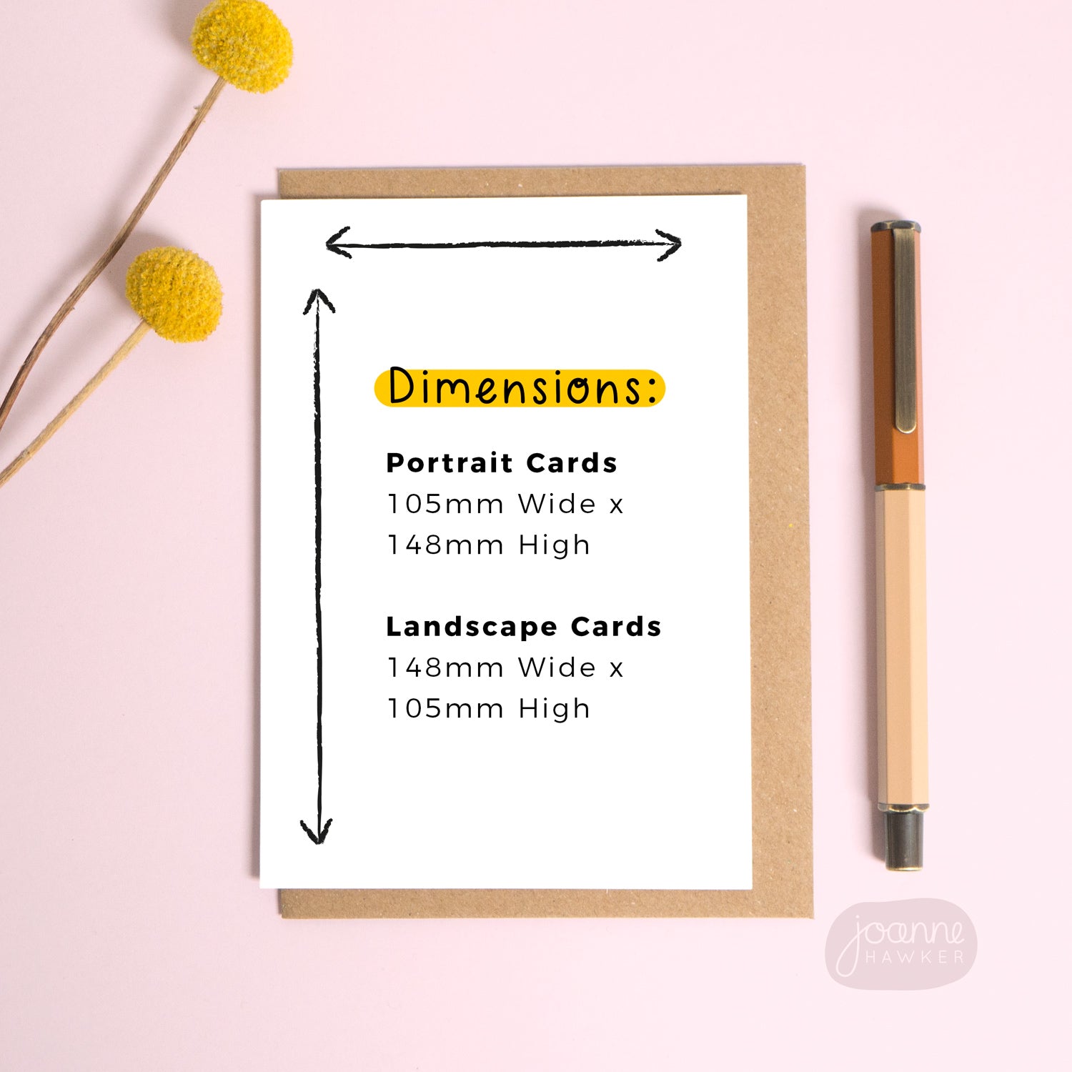 A blank card set on a pink background with a pop of yellow flowers and a pen for scale. The text on the card gives the dimensions in both portrait and landscape format.