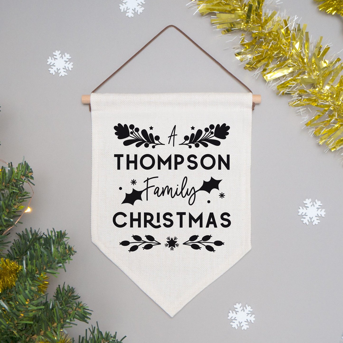 A personalised family Christmas banner flag personalised with your family name and adorned with festive flourishes! Each flag has a black print on natural coloured linen.