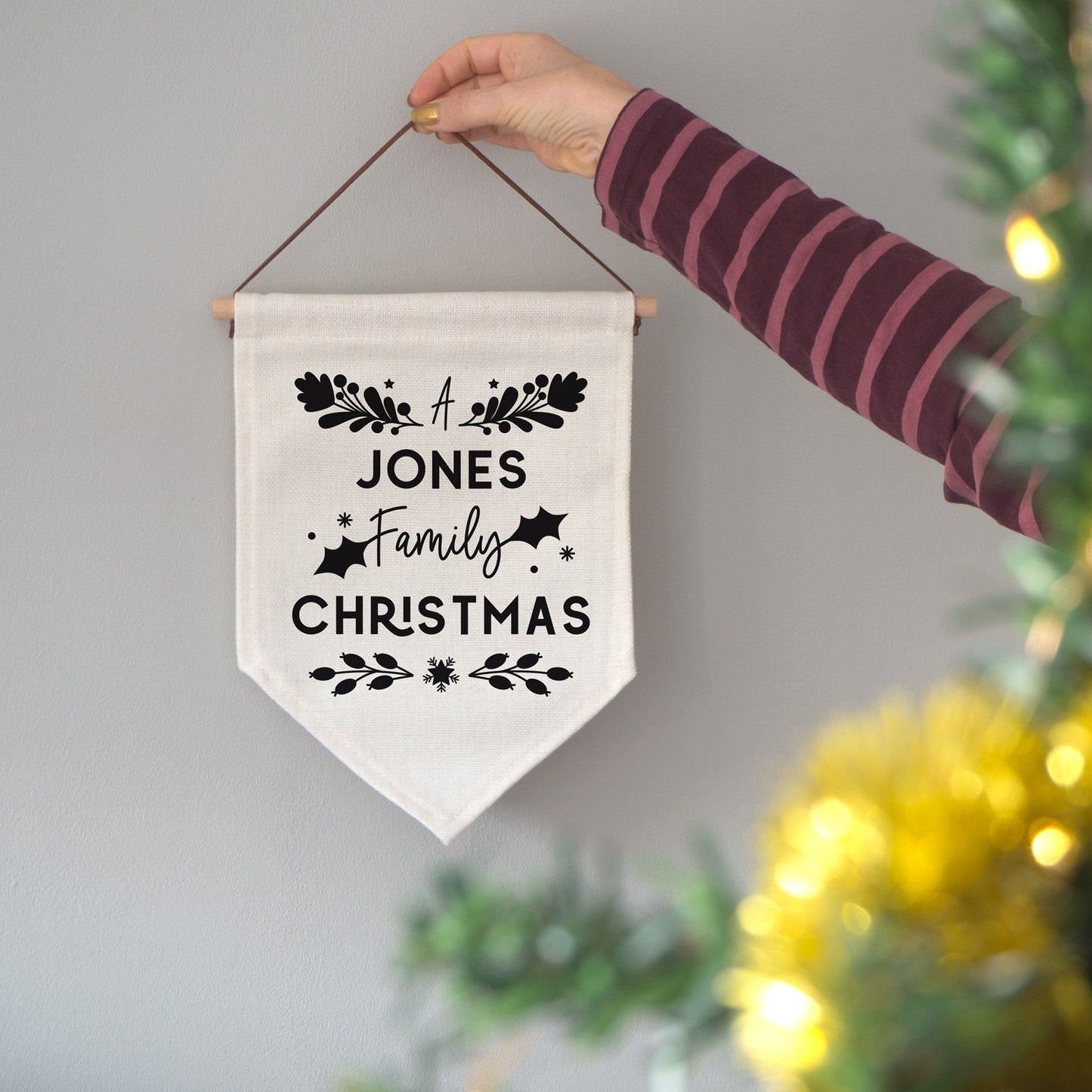 A personalised family Christmas banner flag personalised with your family name and adorned with festive flourishes! Each flag has a black print on natural coloured linen.