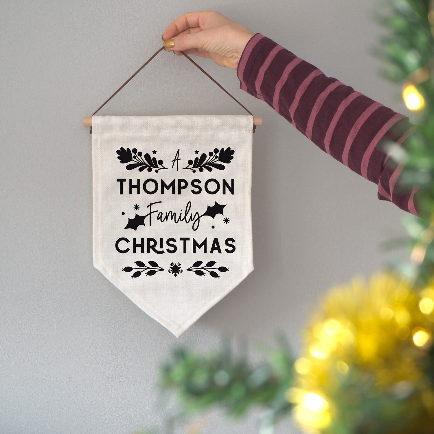 A personalised family Christmas banner flag personalised with your family name and adorned with festive flourishes! Each flag has a black print on natural coloured linen.