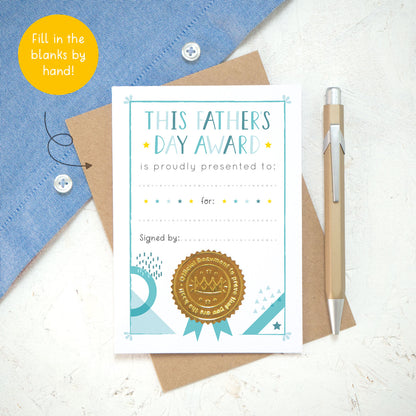 A flat lay shot of the Father's Day award card on a white background with a blue shirt in the top right. This is the blank version of the card that you will receive. The image also shows a yellow bubble with the wording "fill in the blanks by hand!"