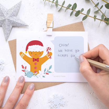 A personalised gingerbread man scratch card with the handwriting element being demonstrated. Shot on a white background with a glittery star and sprig of eucalyptus.