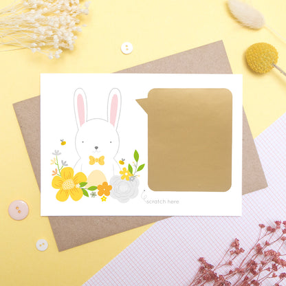A personalised godparent scratch card before it has been scratched off. This is how the cards will arrive. This one has been shot on a yellow background with floral props. It features a white rabbit with a yellow theme.