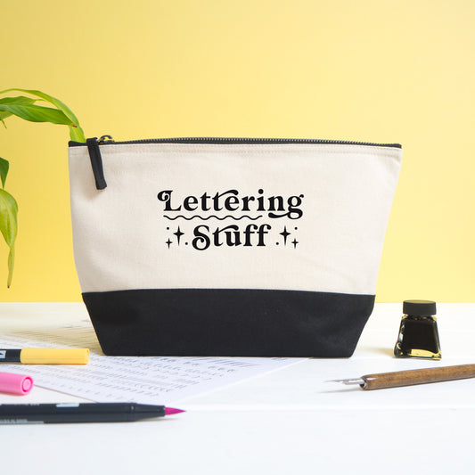 A lettering stuff project bag shot on a white and yellow background with calligraphy materials in the foreground.