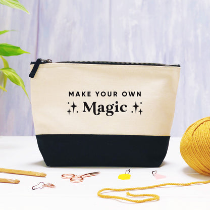 A make your own magic cotton storage bag, natural in colour with a black box bottom base photographed on a purple background with leaves, a ball of yarn and crochet tools.