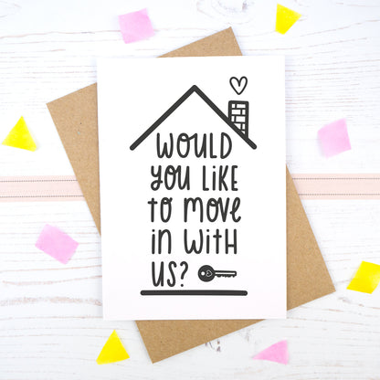 Would you like to move in with us card in black & white, under a roof with a chimney and heart.