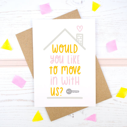 Would you like to move in with us card in pink and orange, under a grey roof and a dark grey key.