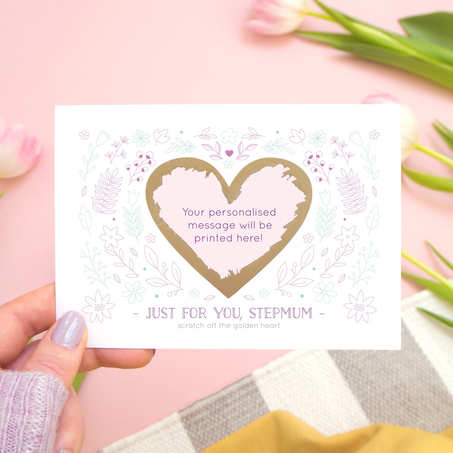 Just for you stepmum scratch card showing where your personalised message will be printed. The card is held over a pink background with tulips and stripy rug.