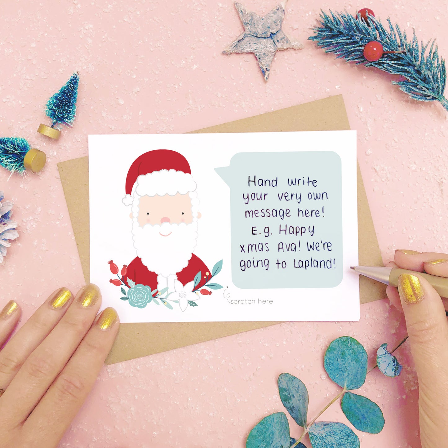 An example of a handwritten message on a personalised scratch card. Shot on a pink background with festive photo props.