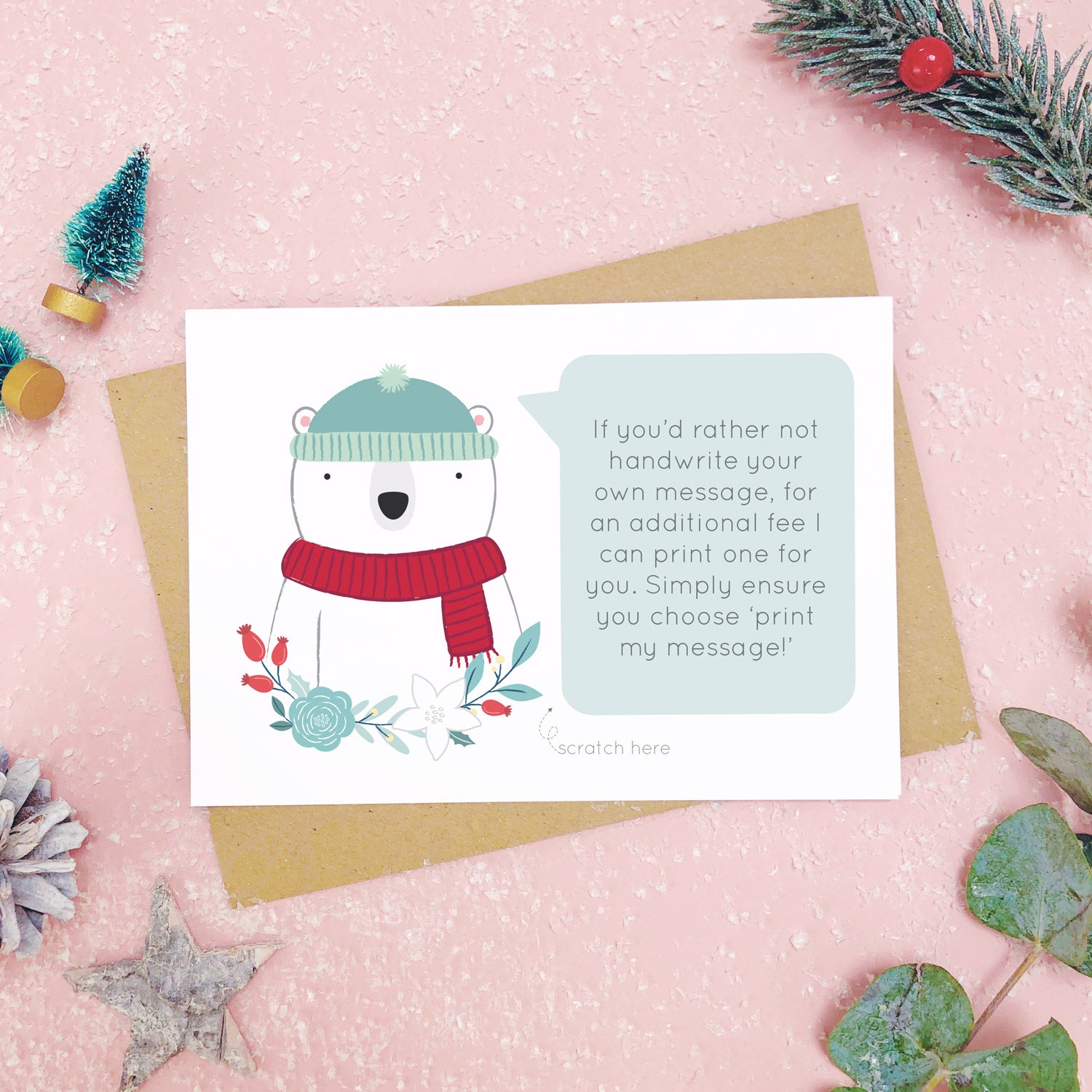 A personalised polar bear scratch card shot on a pink background with festive props in grey and green. This is an example of the printed message option.