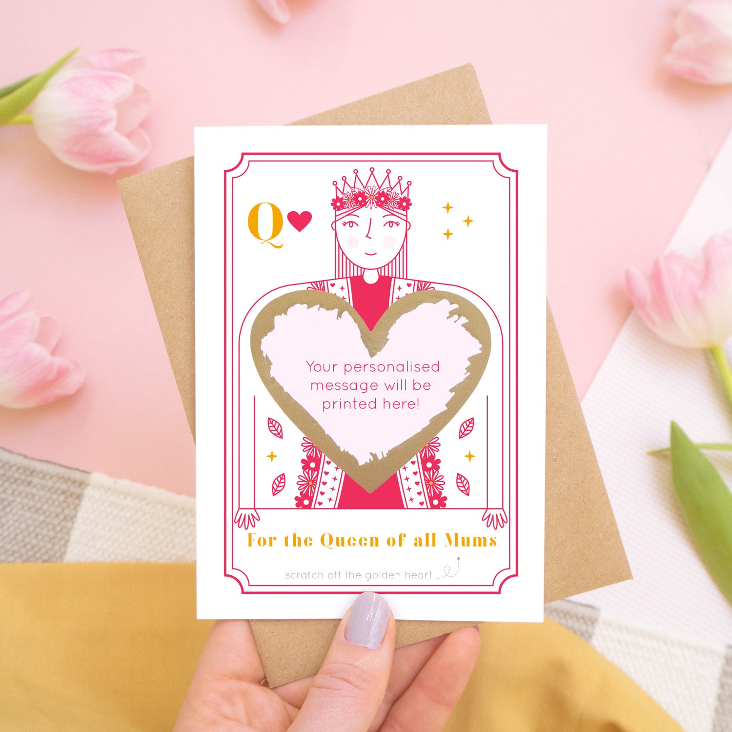 A queen of all mums scratch card showing you where your printed personalisation will go on the card. The card has been scratched off and is being held above pink tulips and a yellow skirt.