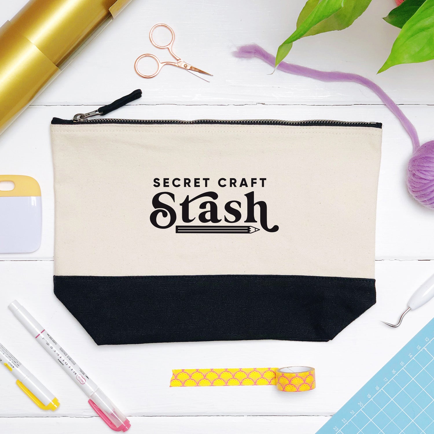 A secret craft stash cotton storage bag, natural in colour with a black box bottom base photographed in a flat lay style surrounded by craft supplies