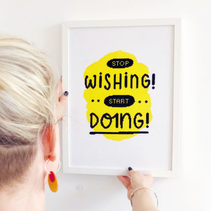 The completed stop wishing start doing modern xstitch kit in yellow and framed in a white frame