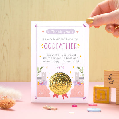 A ‘thank you for being my godfather’ certificate card with a shiny gold seal in the purple colour palette standing in front of a yellow and pink background with building blocks, buttons and dry flowers.