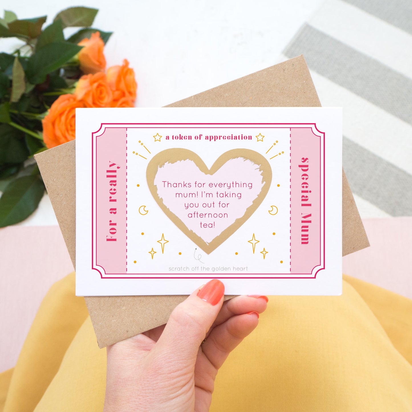 The token of appreciation scratch card showing you an example of a personalised message. The card is shot being held over a pink skirt with roses in the background. The card is pink, red and gold in colour.