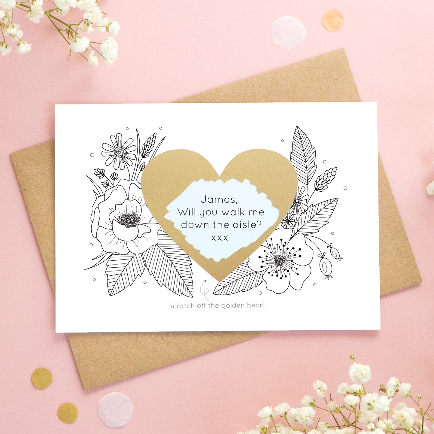 A personalised wedding scratch card shot on a pink background with white flowers. The golden heart has been scratched revealing a blue heart and a proposal asking to be walked down the aisle!