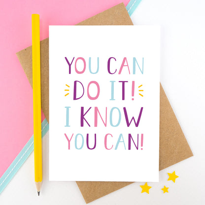 You can do it, I know you can! - Positive encouragement card photographed on a pick and white background separated with a teal ribbon. Also featuring a yellow pencil for scale. This version is in pink, purple and blue colour palette.