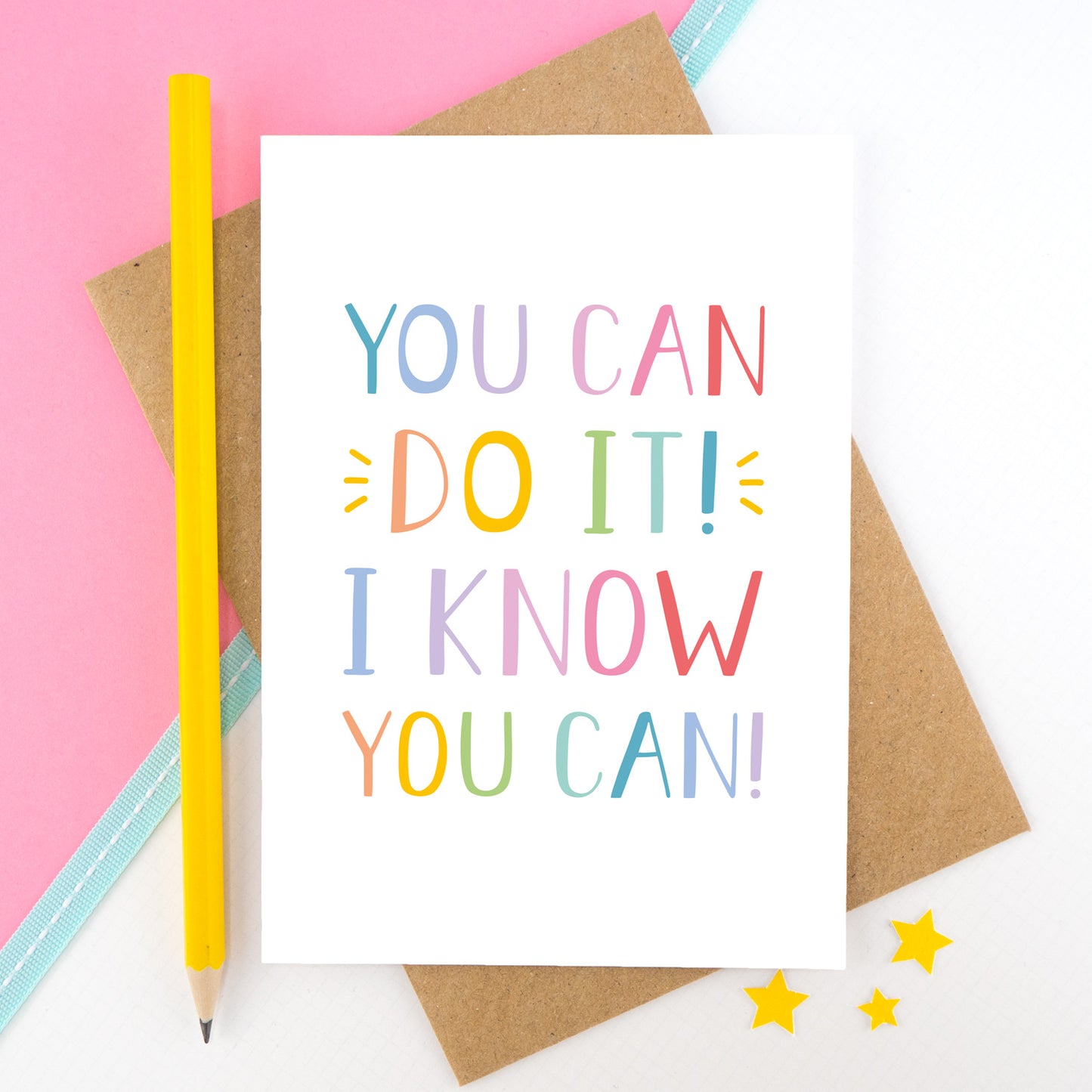 You can do it, I know you can! - Positive encouragement card photographed on a pick and white background separated with a teal ribbon. Also featuring a yellow pencil for scale. This version is in a rainbow colour palette.