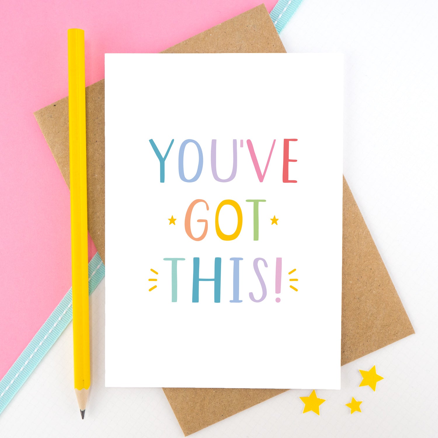 You've got this! A positive encouragement card photographed on a pink and white background with a teal ribbon and bright yellow pencil. The lettering on this card is in rainbow tones.