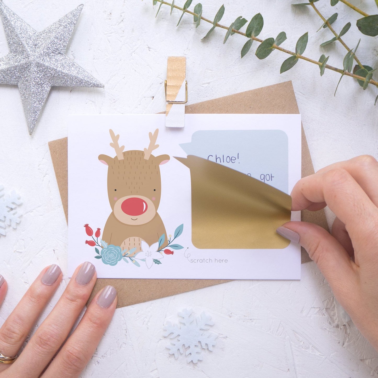 Personalised reindeer secret message Christmas scratch card with the gold panel being applied.
