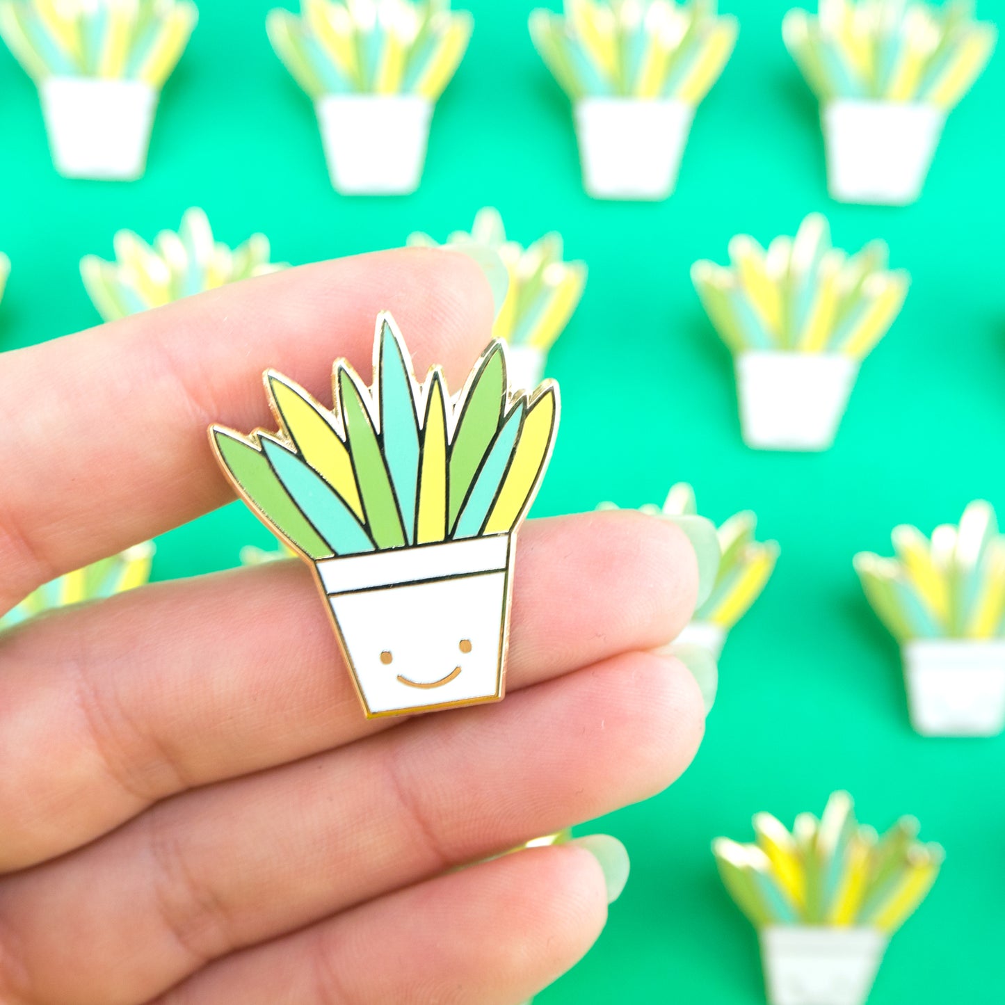 Aloe Vera Hard Enamel Pin in a happy plant pot, hand for scale