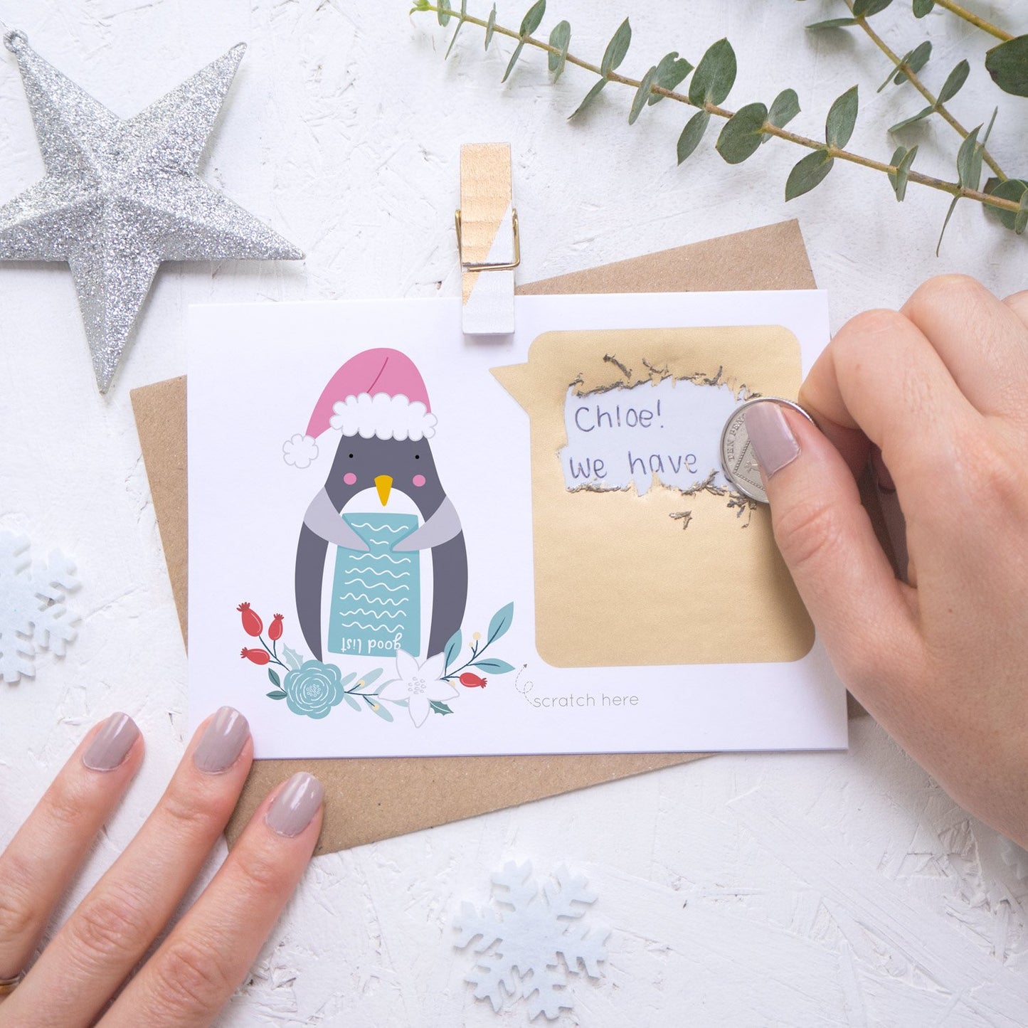 Personalised Penguin secret message Christmas scratch card being scratched off with a coin.