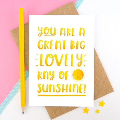 A yellow hand lettered love and friendship card featuring the words 'you are a great big lovely ray of sunshine'.